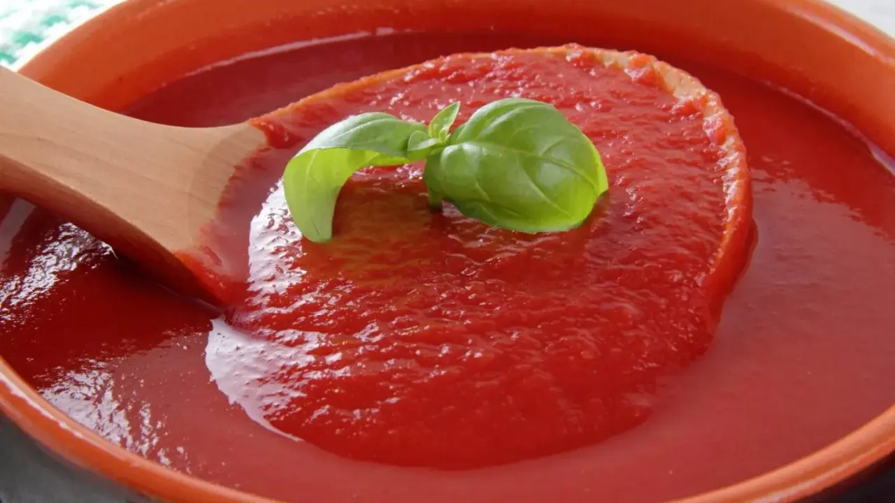 Gęsty, domowy ketchup z pomidorów, z listkiem bazylii na drewnianej łyżce. Idealny przepis na lato!