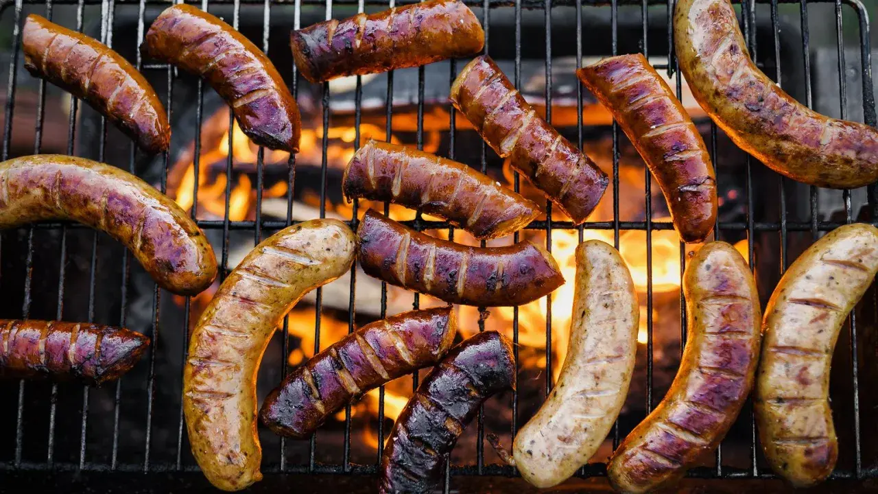 A variety of kiełbasa z grilla piecze się na ruszcie nad płomieniami.