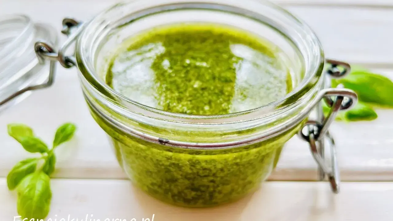 Słoiczek pełen aromatycznego pesto z bazylii, obok świeże listki. Idealne do makaronu i kanapek.