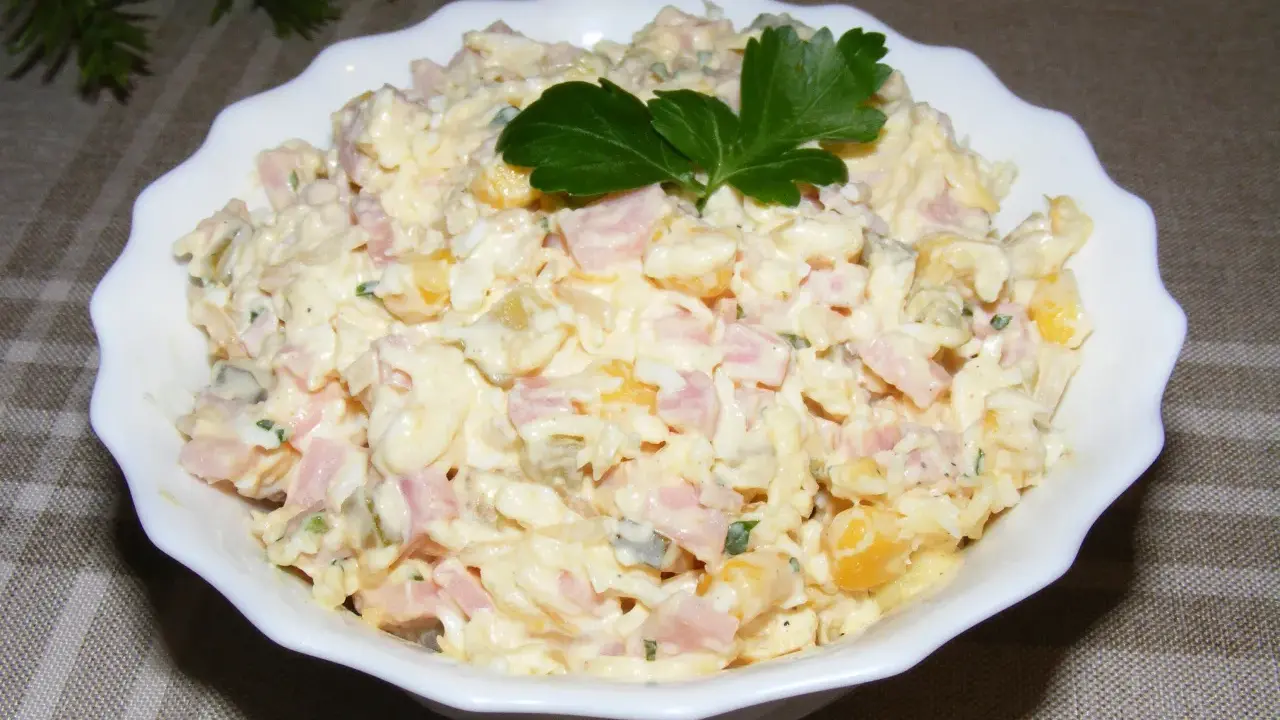 Pyszna sałatka na Wielkanoc z szynką, jajkiem i kukurydzą, udekorowana natką pietruszki.
