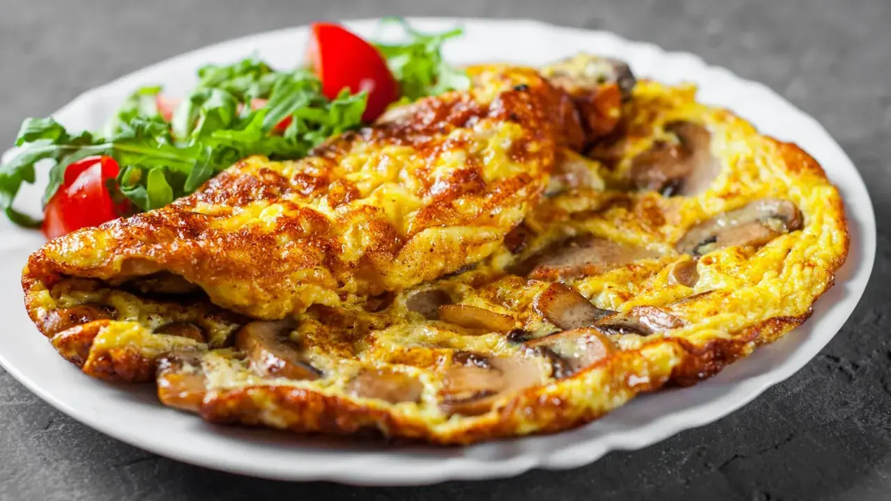 Złocisty omlet z pieczarkami, podany z sałatką z rukoli i pomidorków. Pyszne śniadanie gotowe!