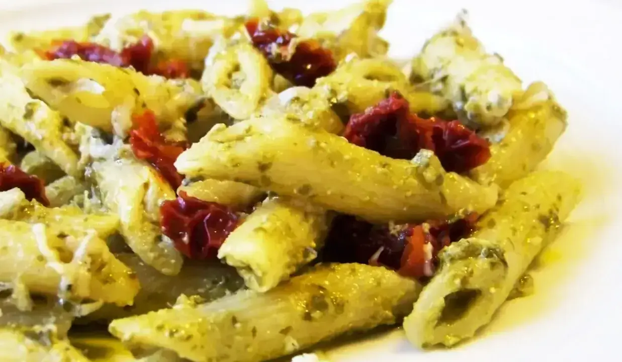 Penne z pesto i kawałkami suszonych pomidorów, posypane parmezanem. Pyszne danie, które zachwyci każdego miłośnika makaronu.