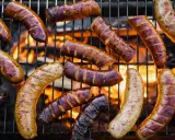 A variety of kiełbasa z grilla piecze się na ruszcie nad płomieniami.