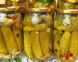 Słoiki z ogórkami kiszonymi, idealne na przepis na ogórki w occie. Widać przyprawy, czosnek i chili.