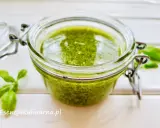 Słoiczek pełen aromatycznego pesto z bazylii, obok świeże listki. Idealne do makaronu i kanapek.
