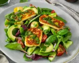 Pyszna sałatka z halloumi, awokado, pomidorkami i ogórkiem, polana zielonym sosem.