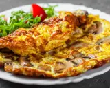 Złocisty omlet z pieczarkami, podany z sałatką z rukoli i pomidorków. Pyszne śniadanie gotowe!