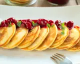 Puszyste pancakes na maślance, polane wiśniowym sosem i ozdobione listkami mięty. Idealne na słodkie śniadanie.