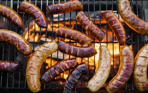 A variety of kiełbasa z grilla piecze się na ruszcie nad płomieniami.