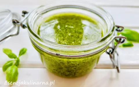Słoiczek pełen aromatycznego pesto z bazylii, obok świeże listki. Idealne do makaronu i kanapek.