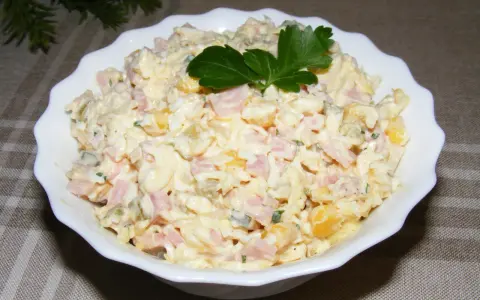 Pyszna sałatka na Wielkanoc z szynką, jajkiem i kukurydzą, udekorowana natką pietruszki.