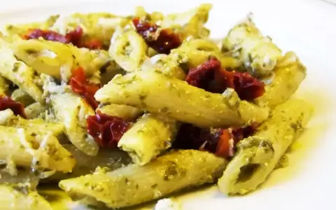 Penne z pesto i kawałkami suszonych pomidorów, posypane parmezanem. Pyszne danie, które zachwyci każdego miłośnika makaronu.