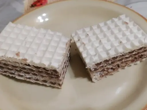 Dwa kwadratowe wafle z kremem czekoladowym, przypominające smakiem wafle z mlekiem w proszku. Idealne na deser.
