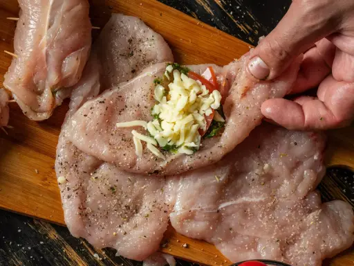 Przygotowanie roladki z kurczaka z serem i ziołami. Mięso doprawione, gotowe do zwinięcia.