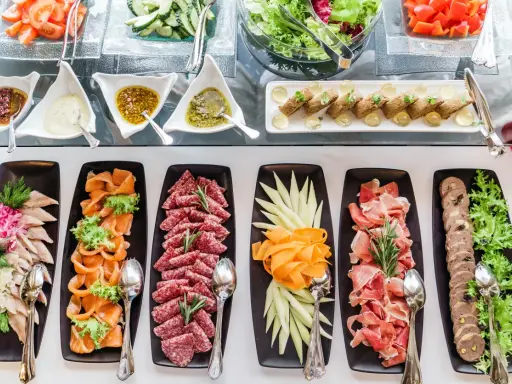 Bogactwo przekąsek i sałatek na imprezę: wędliny, ryby, warzywa i sosy.