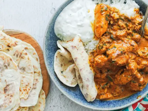 Pyszny butter chicken przepis: kremowy kurczak w sosie pomidorowym z ryżem, jogurtem i chlebkami naan.