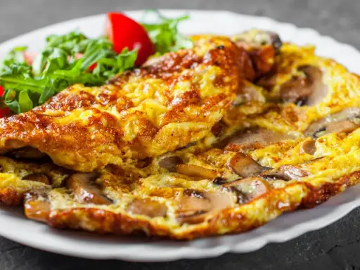 Złocisty omlet z pieczarkami, podany z sałatką z rukoli i pomidorków. Pyszne śniadanie gotowe!