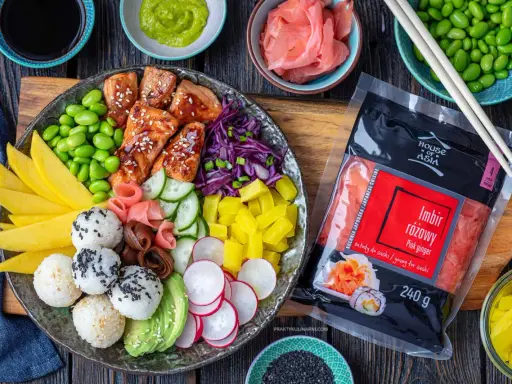 Kolorowy bowl z lososiem, ryżem, mango, awokado, edamame i marynowanym imbirem. Obok opakowanie imbiru różowego.
