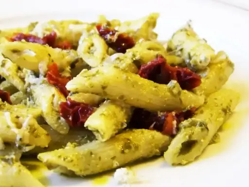 Penne z pesto i kawałkami suszonych pomidorów, posypane parmezanem. Pyszne danie, które zachwyci każdego miłośnika makaronu.