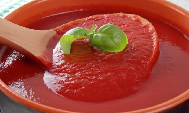 Gęsty, domowy ketchup z pomidorów, z listkiem bazylii na drewnianej łyżce. Idealny przepis na lato!