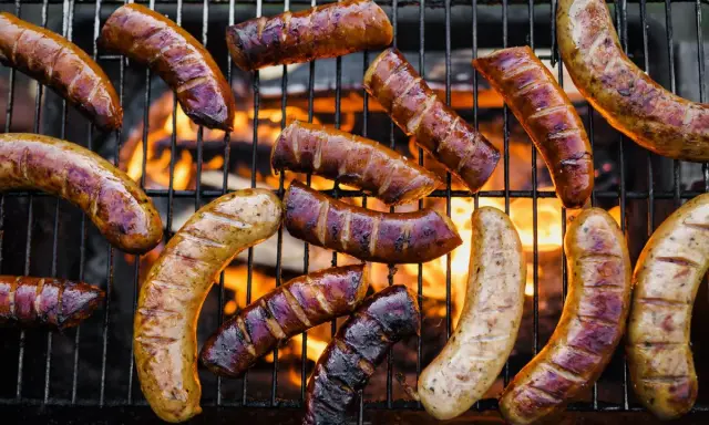 A variety of kiełbasa z grilla piecze się na ruszcie nad płomieniami.
