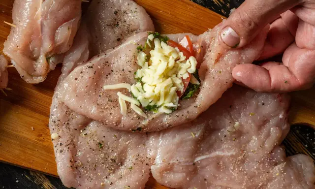 Przygotowanie roladki z kurczaka z serem i ziołami. Mięso doprawione, gotowe do zwinięcia.