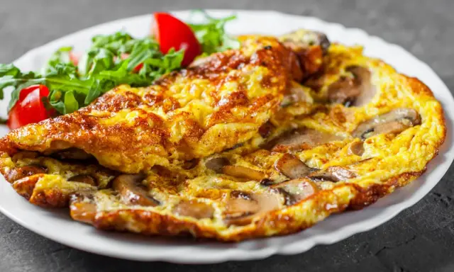 Złocisty omlet z pieczarkami, podany z sałatką z rukoli i pomidorków. Pyszne śniadanie gotowe!