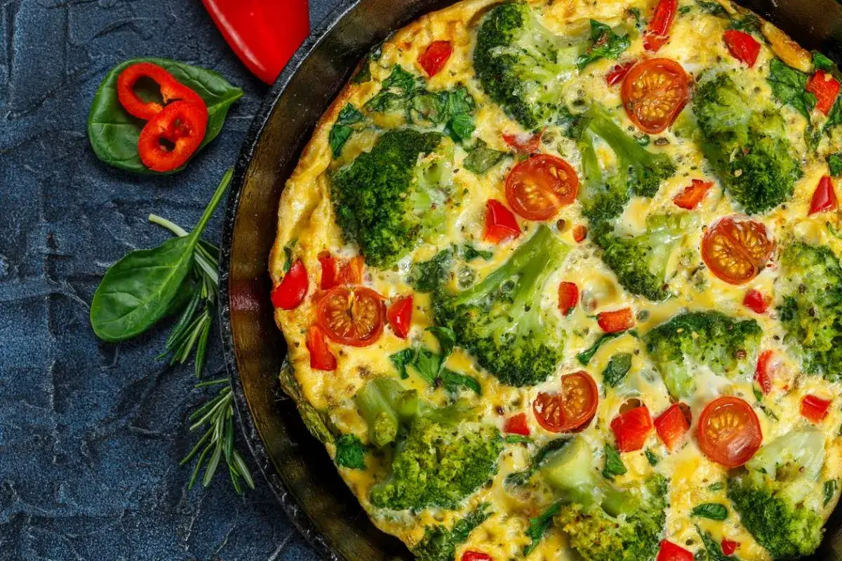 Pyszny omlet na słono z brokułami, pomidorkami i papryką, podany w patelni.