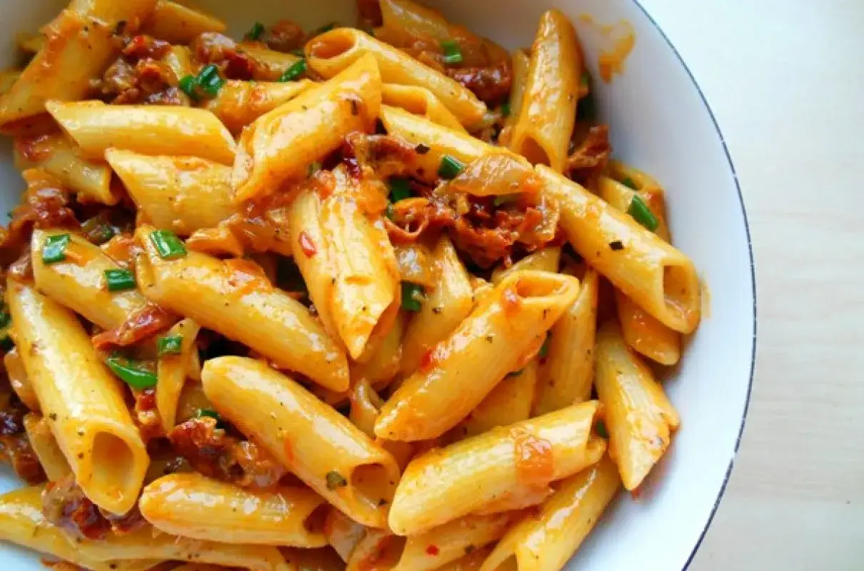 Penne z sosem z suszonych pomidor&oacute;w i zieloną cebulką, apetyczne danie pełne smaku.