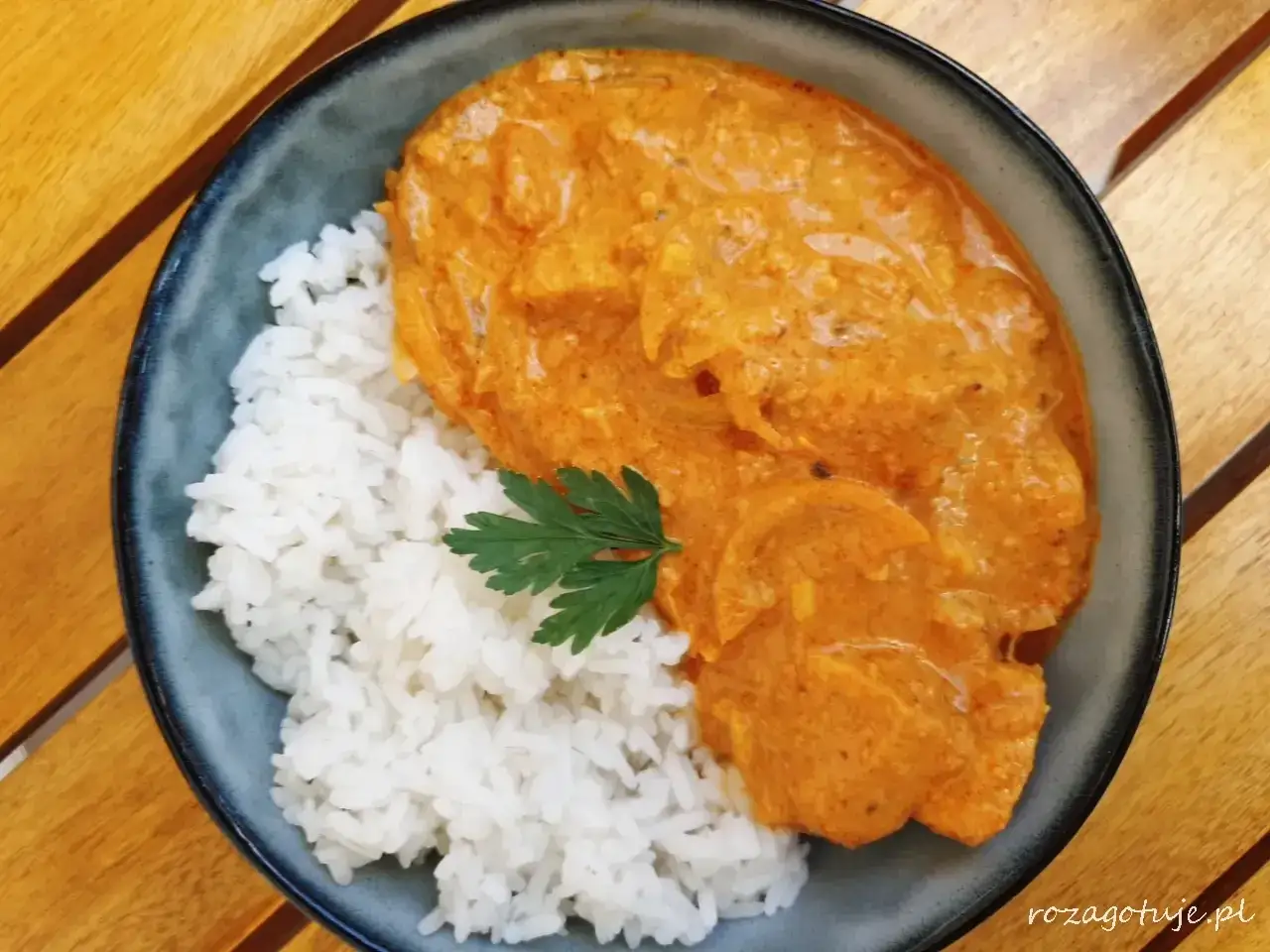 Pyszny butter chicken przepis na talerzu z ryżem i natką pietruszki. Idealny na obiad.