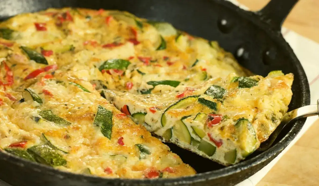 Pyszny omlet z cukinią i papryką, podany w czarnej patelni. Idealny na śniadanie lub lekki obiad.