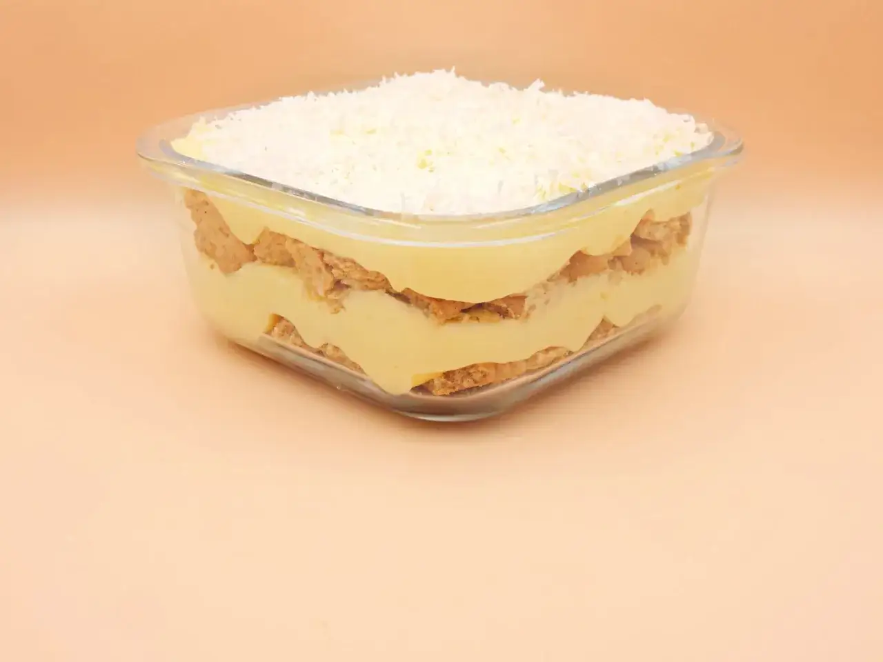 Warstwowy deser z kremem budyniowym i wafelkami, posypany wiórkami kokosowymi. Pyszne rafaello bez pieczenia!